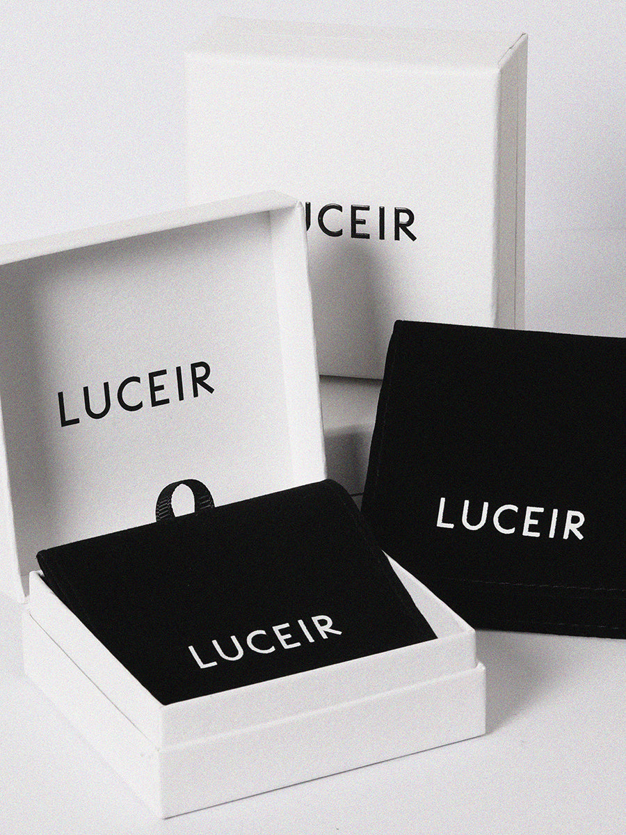 Four Luceir logo'd white boxes randomly place with a black ribbon tied around the central box
